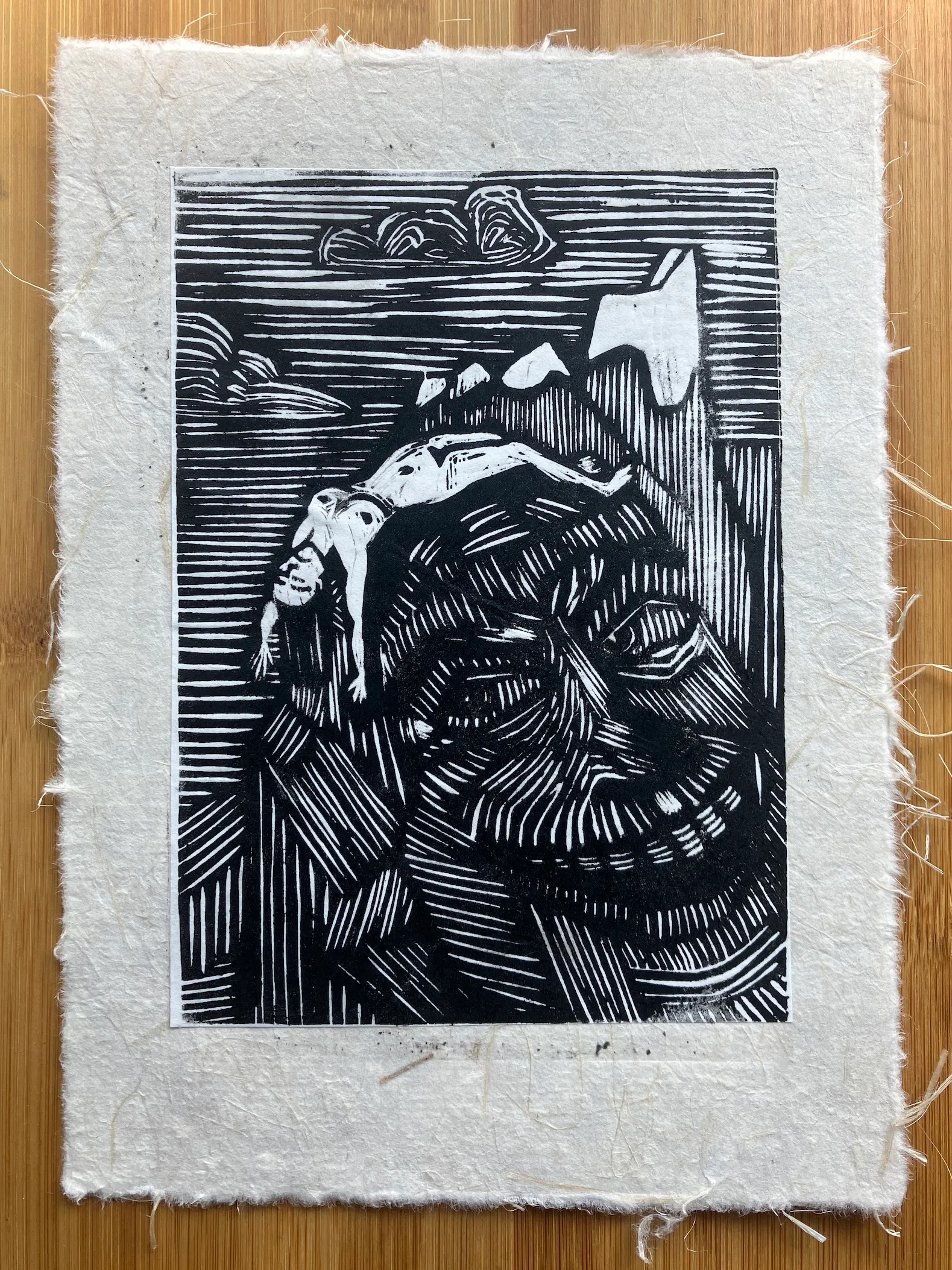 A relief print of various mountain peaks, on the nearest of which a woman's naked body is stretched out across it. The mountain's features have the appearance of a meanacing, grinning face, eyes looking towards the lifeless body.