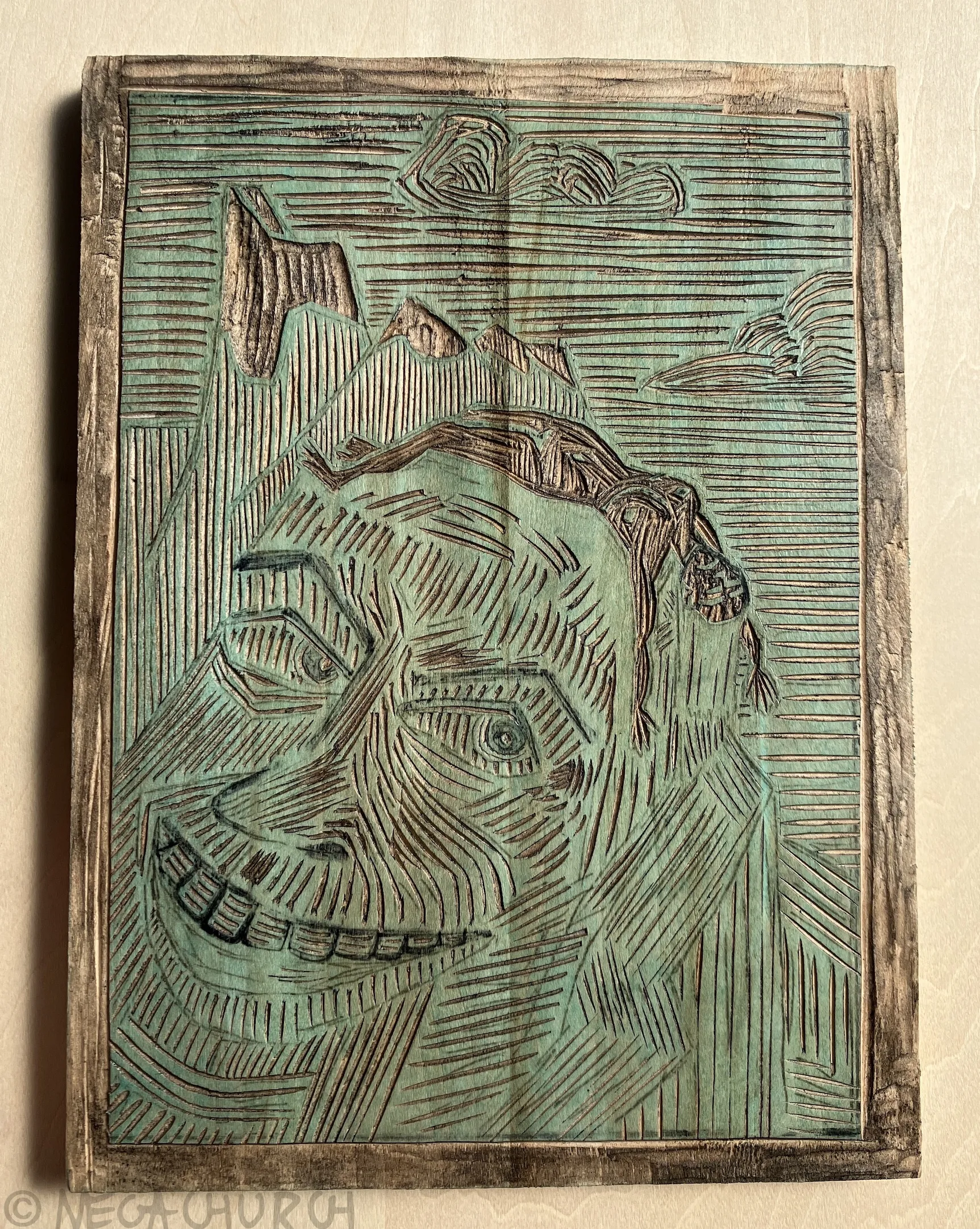 A shina wood plate into which the Alpine Divorce print has been carved.