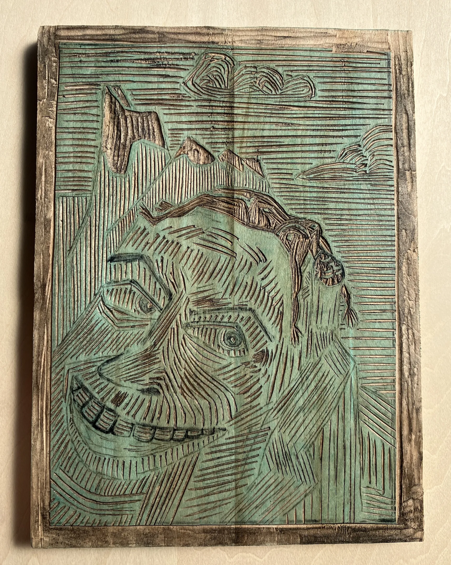 A shina wood plate into which the Alpine Divorce print has been carved.