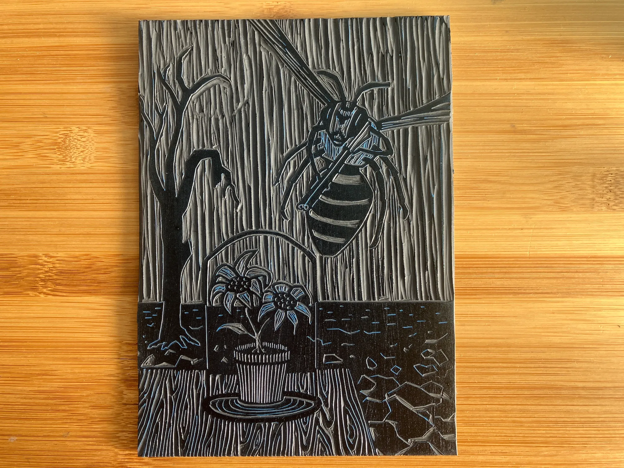 A vinyl plate into which the Bee Angry print has been carved, alongside a small Japanese cutting tool.