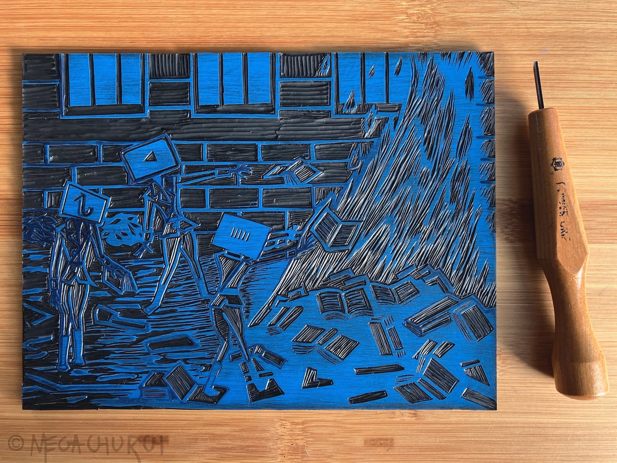 A vinyl plate into which the The End of Literacy print has been carved, alongside a small Japanese cutting tool.