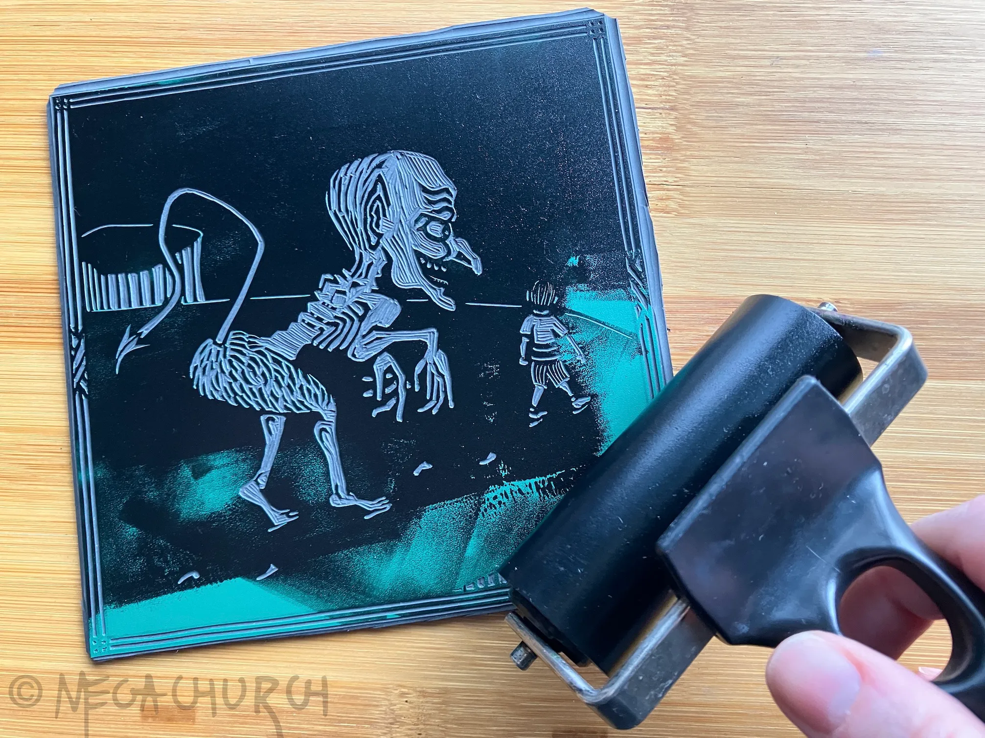 A partially inked vinyl plate into which the Evil Follows print has been carved, alongside a brayer.