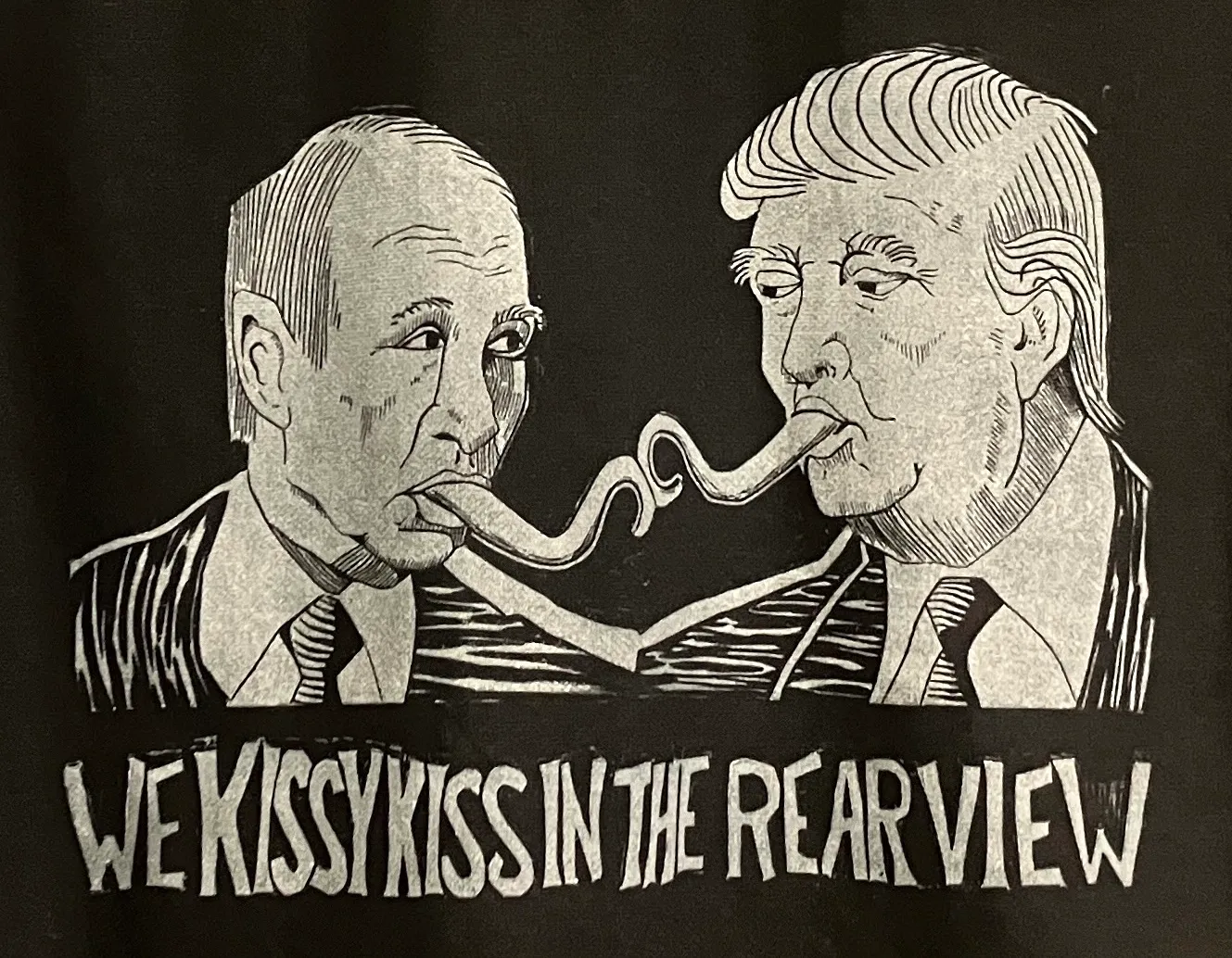 A relief print of Trump and Putin's heads facing each other, elongated tongues protruding from their mouths. Their tongues touch and there is text below reading 'We kissy-kiss in the rearview.'