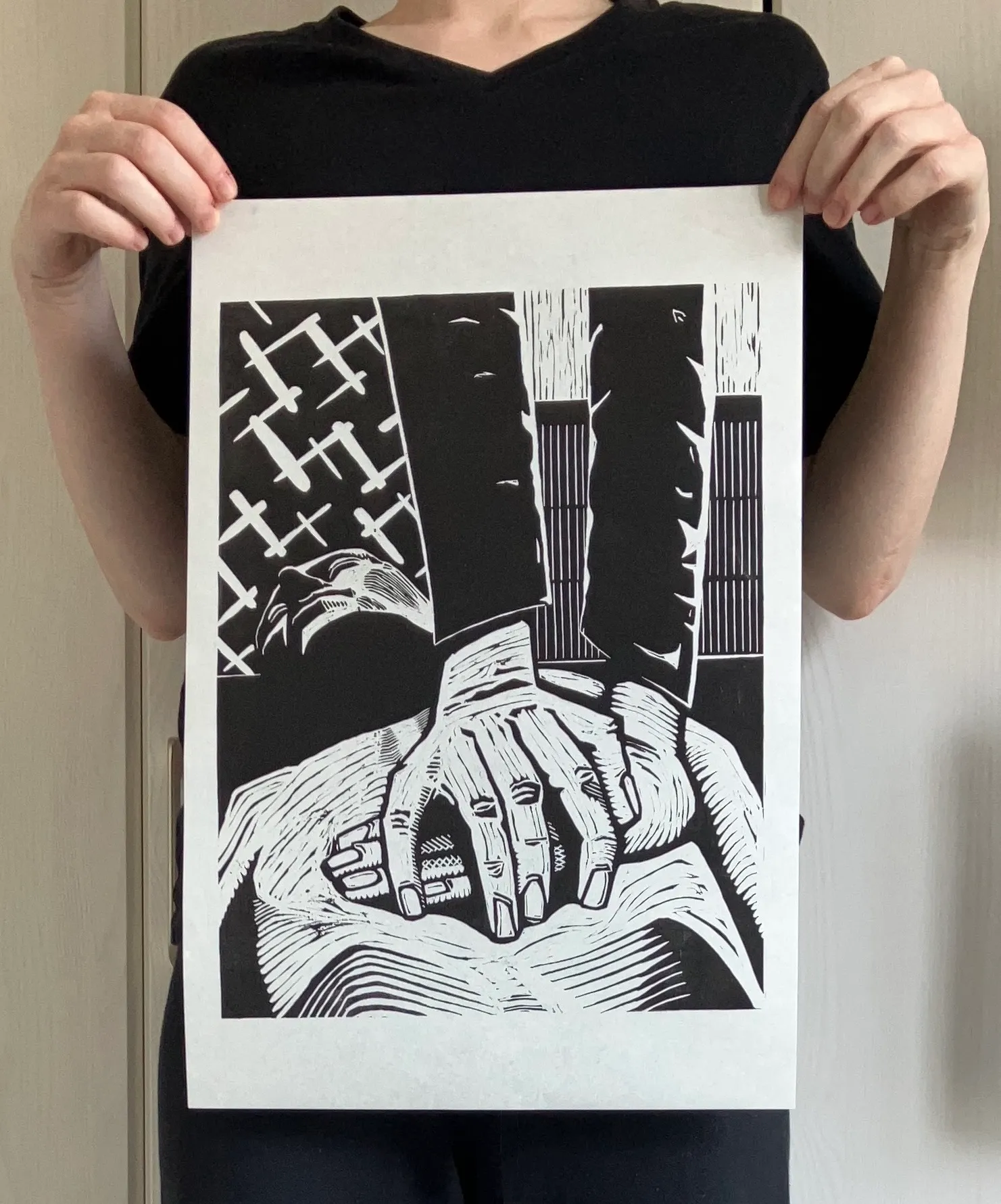 A large relief print showing two hands laid on the chest of an unconscious figure, arms fully extended.