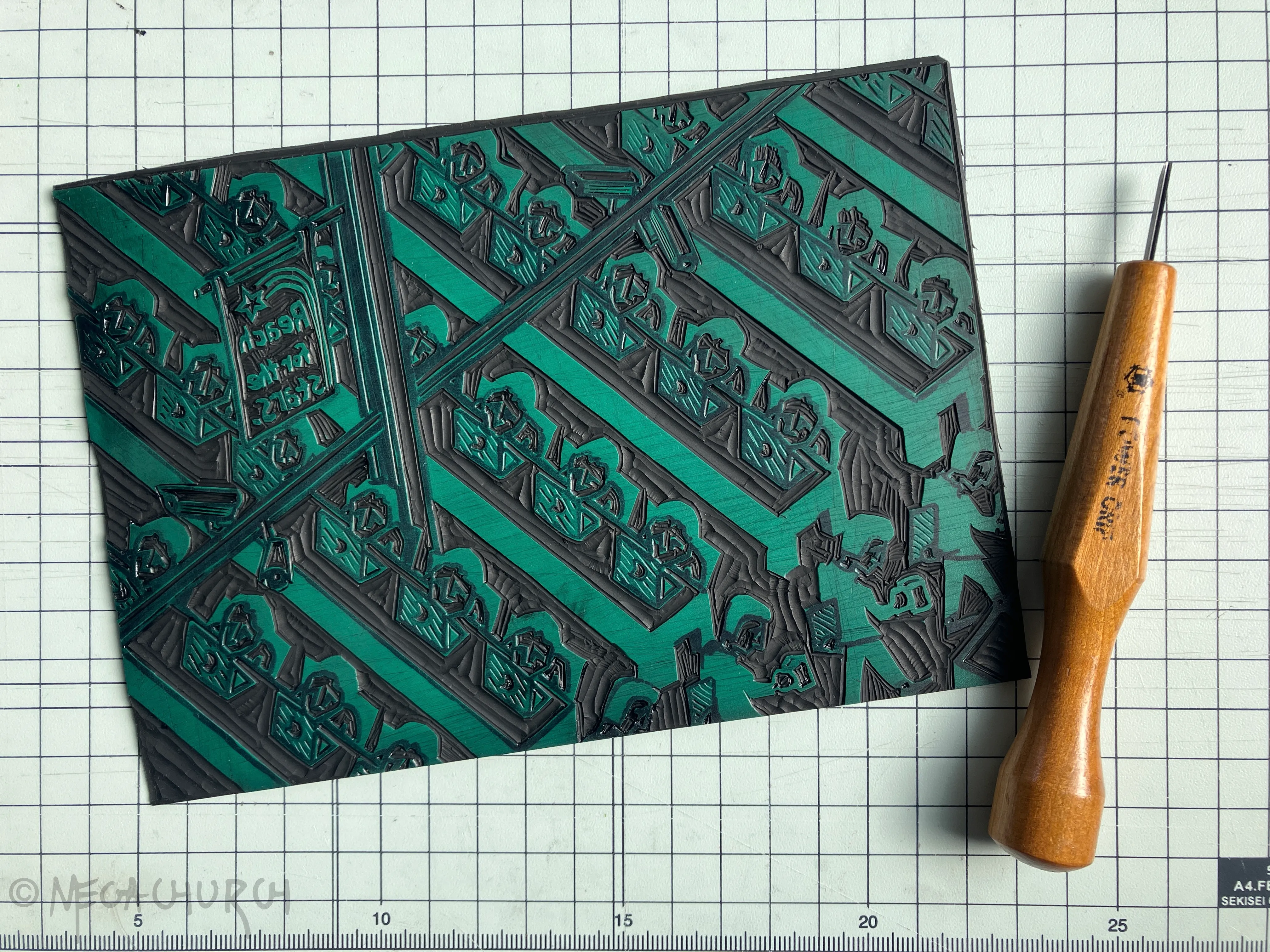 A vinyl plate into which the "Your CEO makes 285 times more than you" print has been carved, alongside a small Japanese cutting tool.