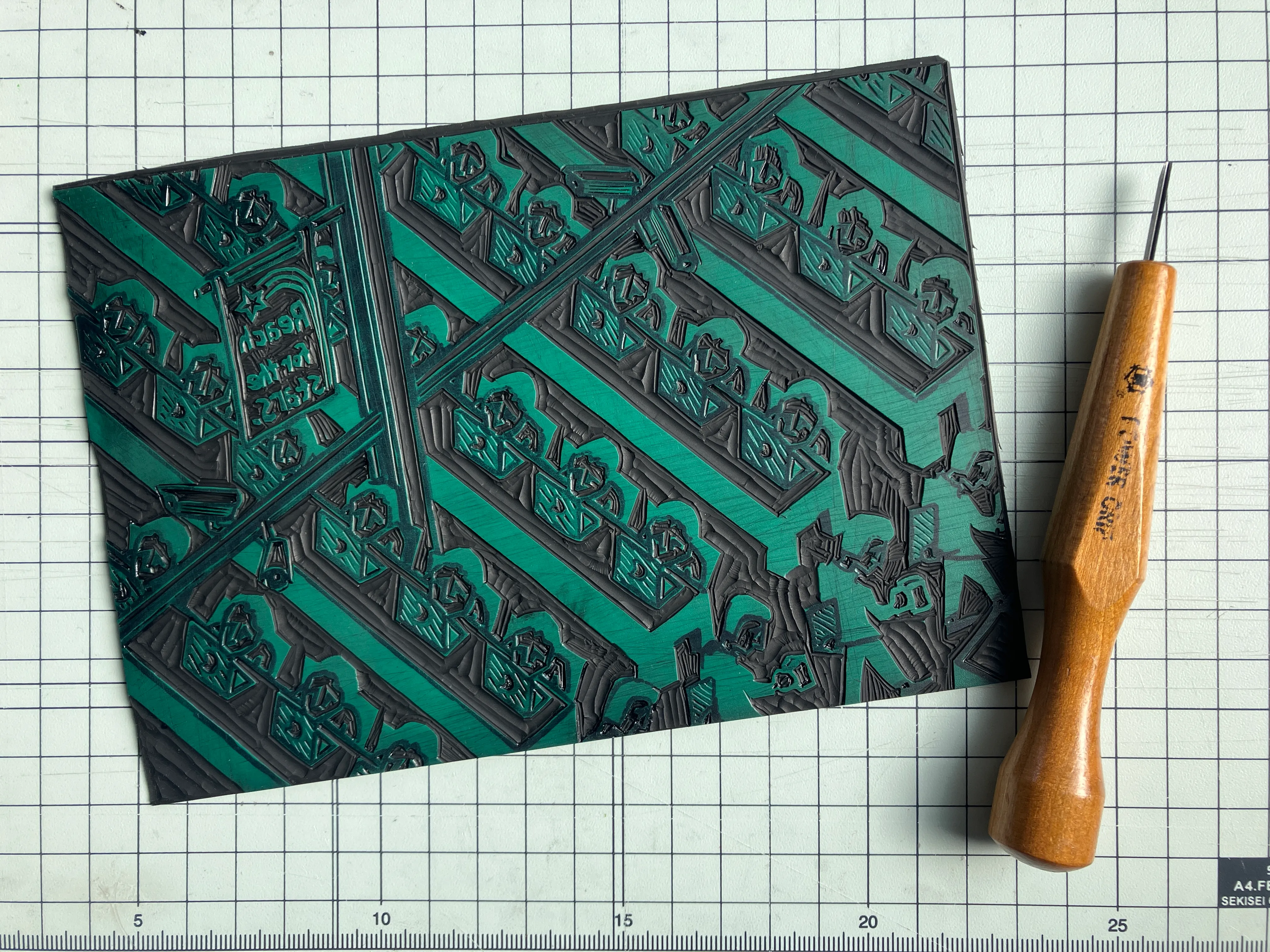A vinyl plate into which the "Your CEO makes 285 times more than you" print has been carved, alongside a small Japanese cutting tool.
